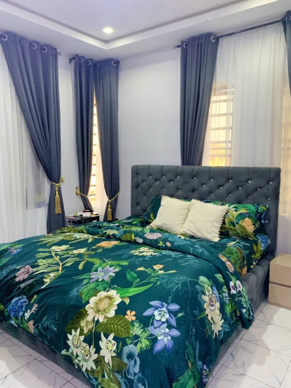 Green flowery polished cotton bedding set on a bed, includes bedsheet, duvet cover, and pillowcases.
